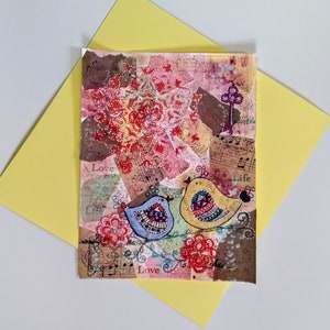 May include: A colorful mixed media art piece featuring two birds with intricate patterns, surrounded by flowers and musical notes. The words "Love" and "Life" are visible in the artwork.