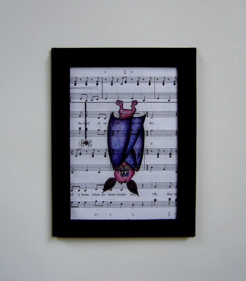 May include: A framed illustration of a purple bat hanging upside down from a music sheet. The bat has a pink face and is drawn in a cartoon style. The music sheet has musical notes and lyrics, including the words "the land of an ud-ed sky" and "a home where no storm clouds rise".