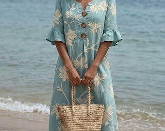 May include: A light blue midi dress featuring a V-neckline, three-quarter length ruffled sleeves, and a front button placket with three brown buttons. The dress is decorated with an all-over white floral embroidery pattern and is paired with a straw tote bag.