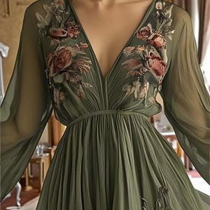 May include: Olive green dress with a deep V-neck and long, flowing sleeves. The bodice features floral embroidery in shades of red, pink, and brown. The dress has a pleated skirt and a fitted waist, creating an elegant silhouette.