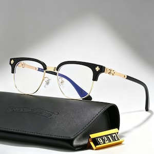 May include: Eyeglasses with a black upper frame and gold rims. The glasses have a distinctive design with decorative crosses on the temples. The glasses are placed on a black case. A gold tag displays the number "9217".