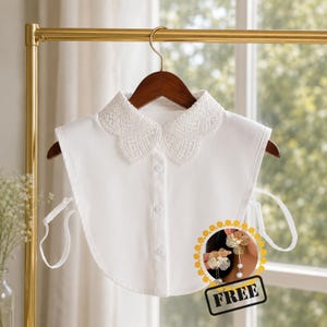 May include: A white detachable collar with a delicate lace trim. The collar has a button-down front and is displayed on a wooden hanger. A small graphic with the word "FREE" is in the bottom right corner.