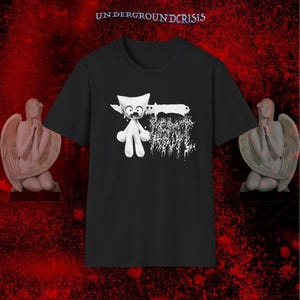 Puede incluir: Una camiseta negra de manga corta con un gráfico blanco de una criatura estilizada que sostiene un cuchillo, con el texto "UNDERGROUNDCRISIS" impreso en la parte superior y texto blanco ilegible junto a la ilustración.