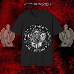 May include: A white ceramic mug with a black handle and the text "But First, Coffee" in a bold, black font. The mug is set against a blurred background, suggesting a cosy setting.