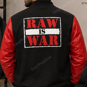 May include: A black varsity jacket with red sleeves and a ribbed collar, cuffs, and hem. The back features a white rectangular patch with the red text RAW IS WAR. The jacket is worn over dark pants and is viewed from the back.
