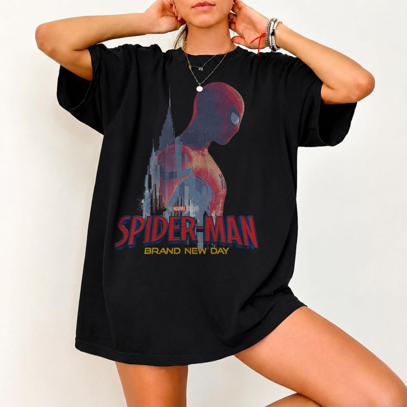 May include: A black short-sleeve t-shirt featuring a graphic of Spider-Man in profile against a city skyline. The text reads Marvel Studios Spider-Man Brand New Day in red and yellow lettering. The design is centered on the chest of the shirt.