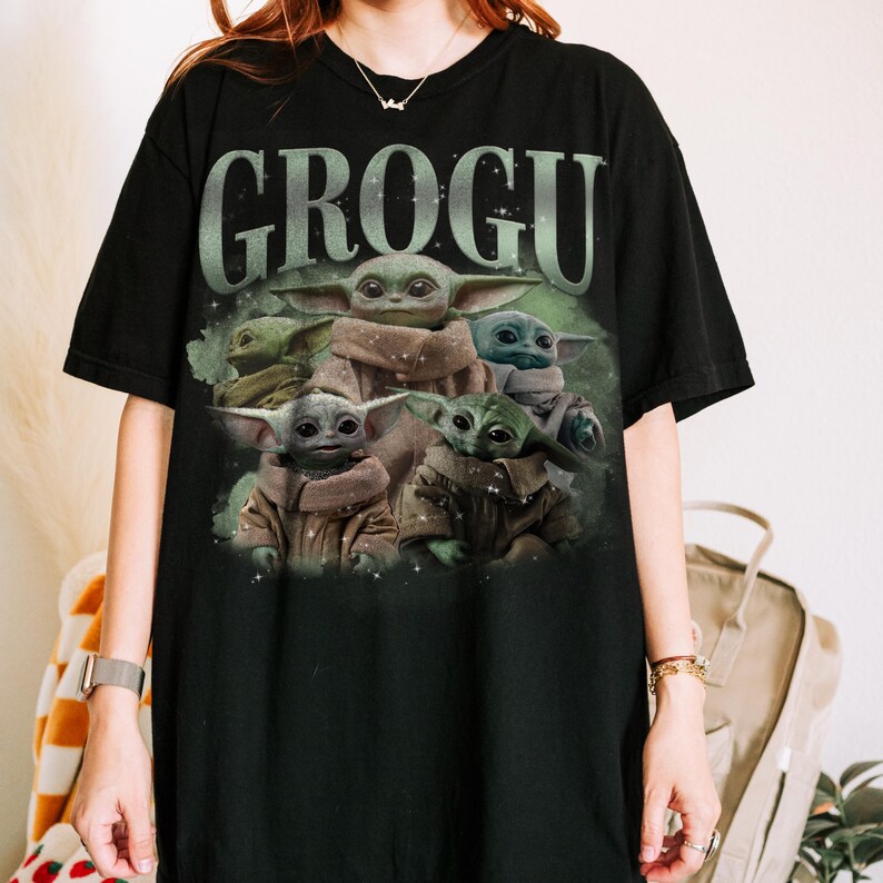 May include: Black t-shirt featuring the word "GROGU" in a green, distressed font above a graphic of Grogu, also known as Baby Yoda, from The Mandalorian. The graphic shows multiple images of Grogu in various poses.