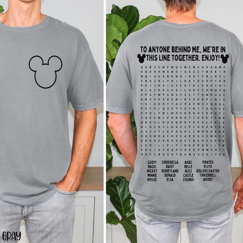 May include: Gray t-shirt featuring a black Mickey Mouse outline on the front. The back of the shirt has the text "TO ANYONE BEHIND ME, WE'RE IN THIS LINE TOGETHER. ENJOY!" with a word search of Disney characters.