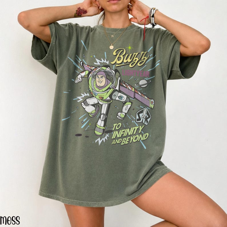 Puede incluir: Camiseta verde oliva con un dise&ntilde;o de Buzz Lightyear de Toy Story. El dise&ntilde;o incluye el texto "Buzz Lightyear" y "To Infinity and Beyond". La camiseta tiene mangas cortas y un corte holgado. Es una prenda informal.