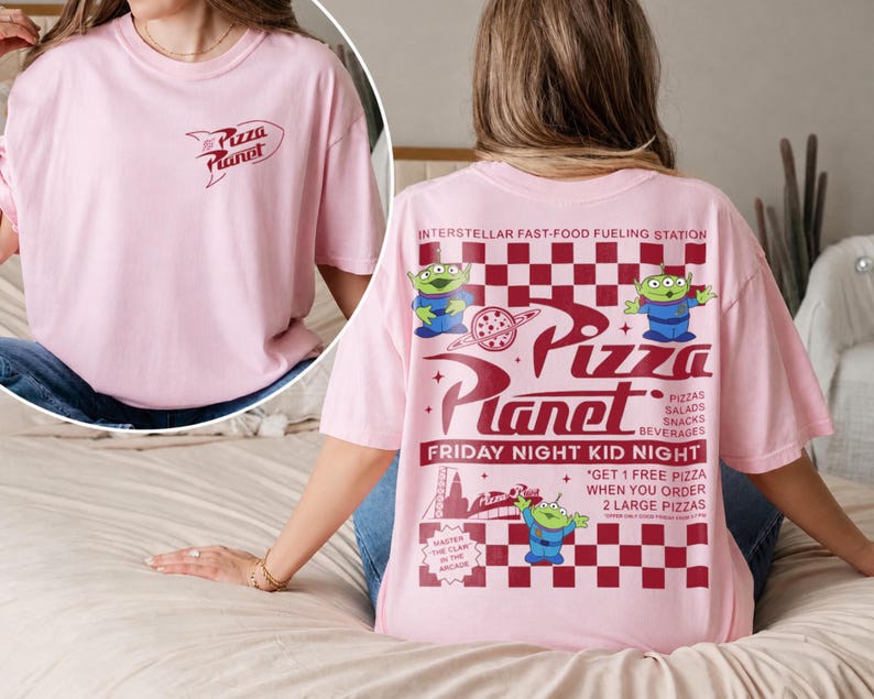 May include: A light pink t-shirt featuring the "Pizza Planet" logo on the front and back. The back design includes the text "Pizza Planet", aliens, and the phrase "Friday Night Kid Night". The shirt is a casual, oversized fit.