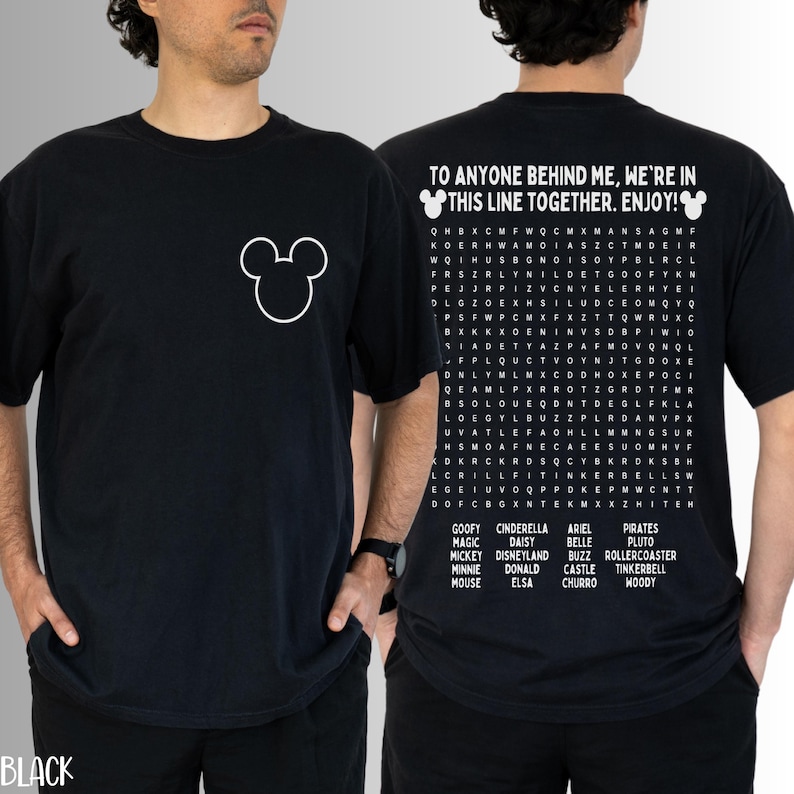 May include: Black t-shirt featuring a white Mickey Mouse outline on the front. The back displays a word search puzzle with Disney-themed words and the phrase "TO ANYONE BEHIND ME, WE'RE IN THIS LINE TOGETHER. ENJOY!"