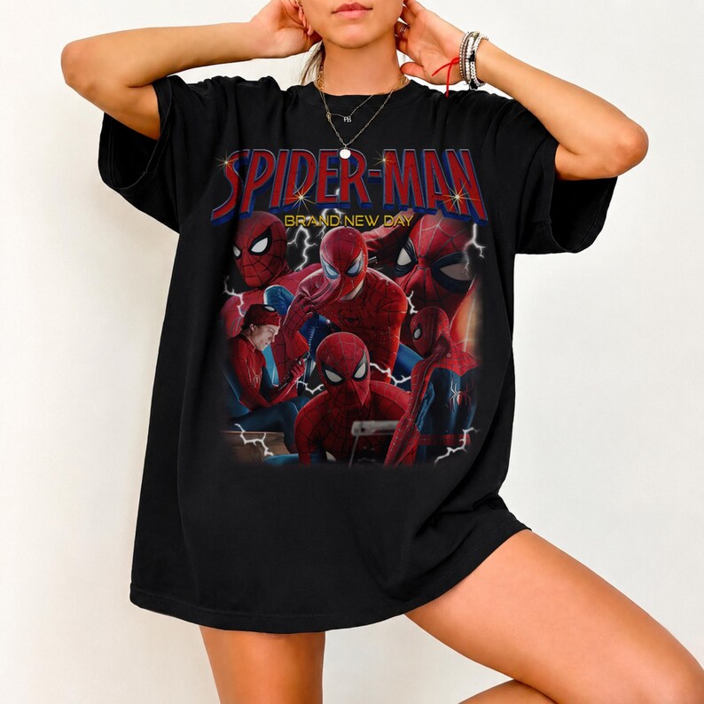 May include: A black short-sleeve t-shirt featuring a graphic print of Spider-Man in various poses. The text SPIDER-MAN is printed in large red letters at the top, with the words BRAND NEW DAY in yellow underneath, surrounded by white lightning bolts.