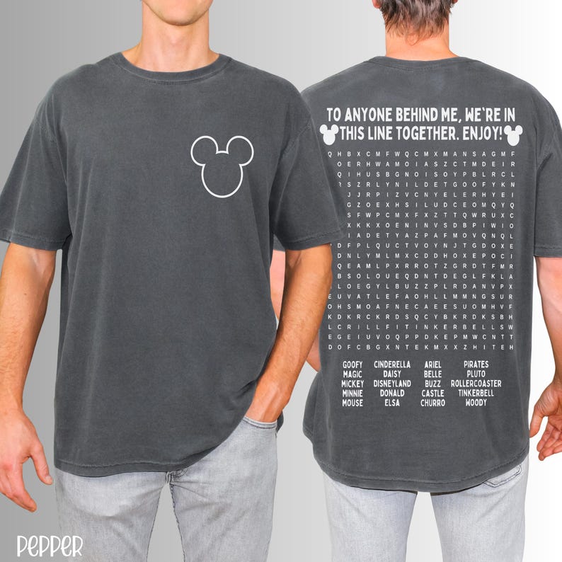 May include: Dark gray t-shirt featuring a white Mickey Mouse head on the front. The back of the shirt has the text "TO ANYONE BEHIND ME, WE'RE IN THIS LINE TOGETHER. ENJOY!" and a word search with Disney characters.