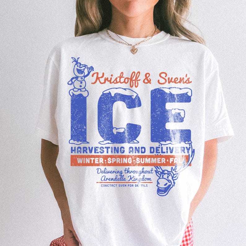 May include: White t-shirt featuring a distressed blue and red graphic. The design includes the text "Kristoff & Sven's ICE" with additional text about ice harvesting and delivery, and a cartoon image of Olaf and Sven.