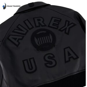 May include: Black leather jacket with the word "AVIREX" arched across the back, along with a circular emblem and the letters "USA". The jacket has a ribbed hem and a buttoned collar. The brand name "FOUAZ TRADERS" is in the top left corner.