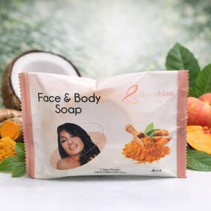 May include: A package of Face & Body Soap with a woman's image, turmeric, and a peach. The soap package is white with pink trim and features the brand name. The image includes a coconut, turmeric roots, and peach slices.