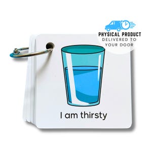 Op de afbeelding: Een vierkante witte flitskaart die door een metalen ring wordt vastgehouden, met een blauwe illustratie van een glas gevuld met water en de zwarte tekst "I am thirsty" onder de afbeelding op de kaart gedrukt.