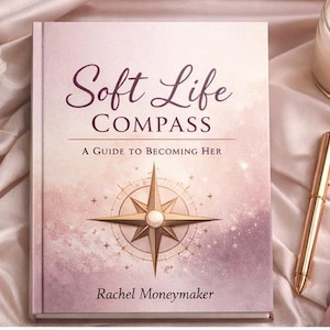 以下が含まれることがあります： 「Soft Life Compass」というタイトルの本。表紙には金のコンパスのデザインが施されている。本は柔らかいピンク色の背景に置かれ、横には金のペンが置かれている。著者はレイチェル・マネーメーカーです。