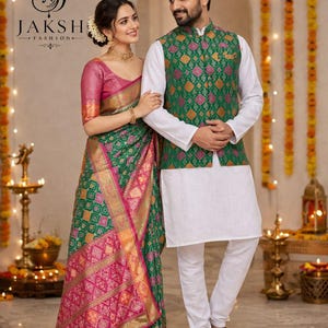 May include: A couple in traditional Indian attire. The woman wears a green and pink sari with gold accents, and the man wears a white kurta and pants with a green patterned vest. The image includes the text "JAKSH FASHION".