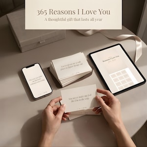 以下が含まれることがあります： 「365 Reasons I Love You」のテキストが入ったギフトセットには、カードの束、スマートフォン、タブレットが含まれています。カードにはロマンチックなフレーズが書かれています。タブレットにはボックスのグリッドが表示されます。ギフトボックスが背景にあります。