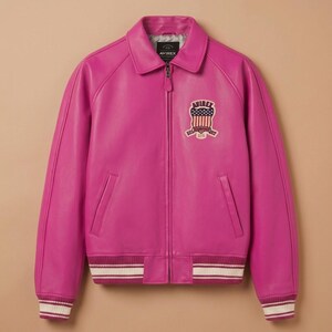 May include: A vibrant fuchsia leather jacket with a classic bomber silhouette. Features a collared neckline, zip-up front, and ribbed cuffs and hem with white stripes. An embroidered patch with an American flag design is on the chest.