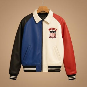 Peut inclure: Une veste color-block avec un col blanc, une manche droite noire, un panneau avant bleu, un panneau avant gauche blanc et une manche gauche rouge. La poitrine pr&eacute;sente un logo &eacute;cusson Avirex brod&eacute; avec des &eacute;toiles et des rayures. Elle poss&egrave;de une fermeture &eacute;clair frontale et des poignets et un ourlet c&ocirc;tel&eacute;s noirs avec des rayures blanches.