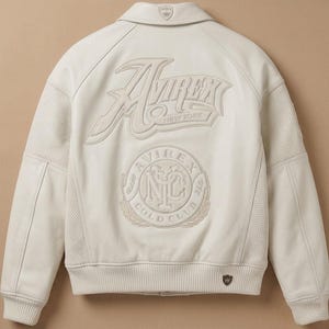 May include: Cream-colored leather jacket with the "Avirex New York" logo embroidered on the back. Features a "Cold Club" emblem and a small logo on the collar. The jacket has perforated panels on the sides.