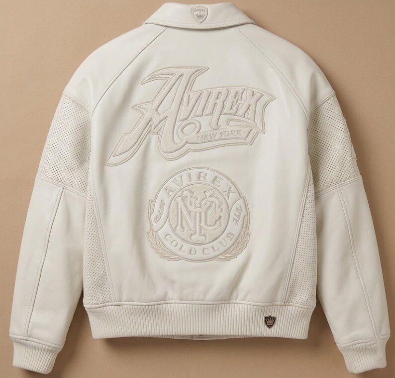 May include: Cream-colored leather jacket with the "Avirex New York" logo embroidered on the back. Features a "Cold Club" emblem and a small logo on the collar. The jacket has perforated panels on the sides.