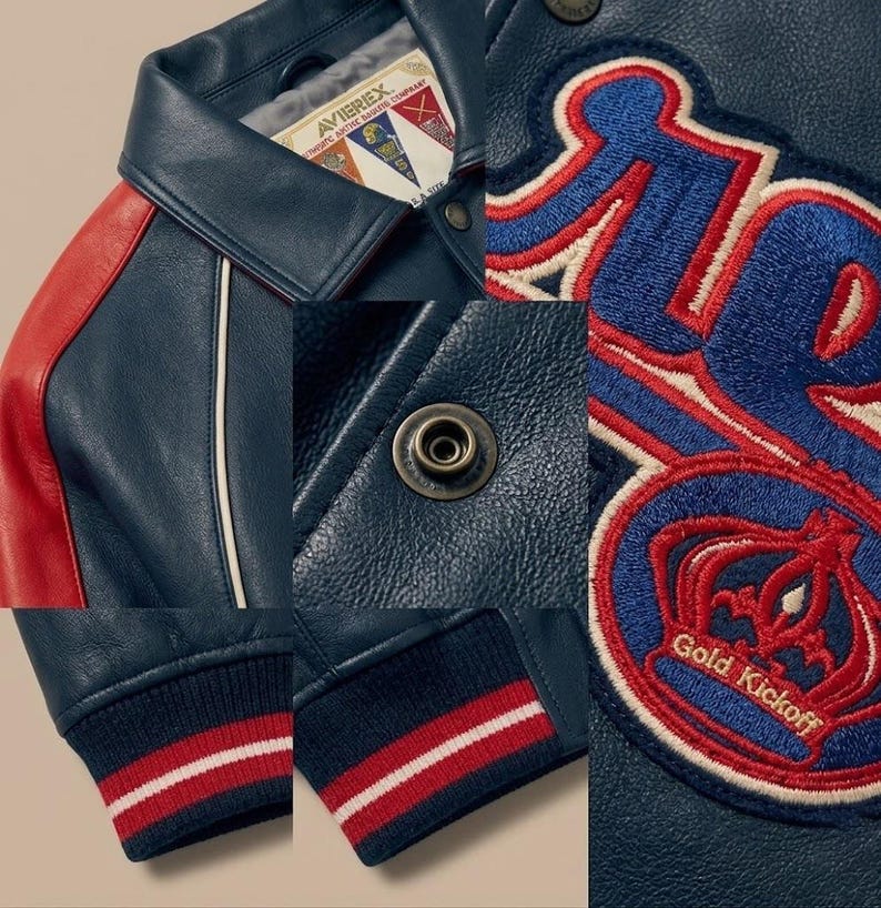 May include: A navy blue leather jacket with red and white accents. Features include a red shoulder panel, white piping, and a navy blue ribbed cuff with red and white stripes. The jacket has a patch that says "Gold Kickoff".