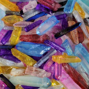 May include: A collection of colorful crystal points in various shades of blue, purple, pink, yellow, and red. The points are arranged in a random pattern and are all approximately the same size.