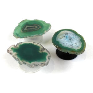 May include: Three green agate slice phone grips. Each grip features a different pattern of green and white agate.