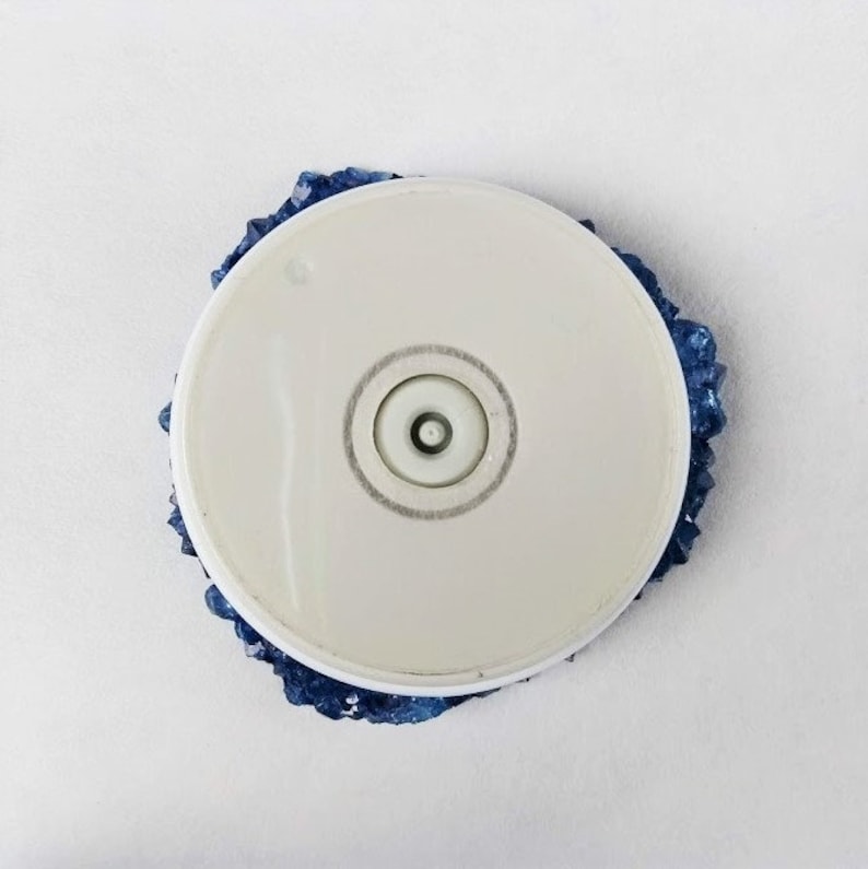 May include: A white round base with a blue crystal-like design around the edge. The base has a small round hole in the center.