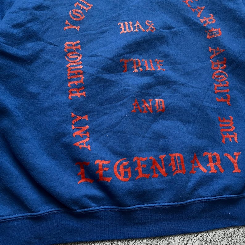 May include: A blue sweatshirt with red lettering. The text includes the phrases "ANY RUMOR YOU HEARD ABOUT ME WAS TRUE AND LEGENDARY". The sweatshirt is made of a soft material.