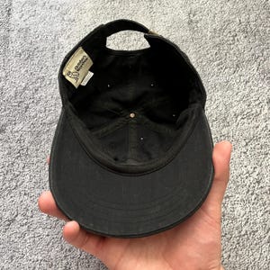 Puede incluir: Gorra de b&eacute;isbol negra con visera curva y correa ajustable. El interior presenta una etiqueta con el texto "October's Very Own" y un logotipo. La gorra est&aacute; hecha de tela duradera y tiene un estilo cl&aacute;sico e informal.