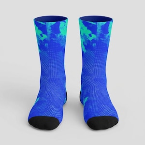 May include: A pair of crew socks with a vibrant blue and teal abstract design. The socks feature a textured pattern and black toes and heels. The top of the socks are a darker shade of blue.