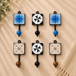 May include: A set of six wall hooks featuring square decorative tiles with varied patterns. The hooks have black metal frames and stems, with round knobs in blue, black, or brown. Each hook includes a small circular loop at the top for mounting.