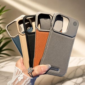May include: Five mobile phone cases in a range of colours: blue, beige, black, orange, and grey. Each case has a metallic camera frame and a textured, leather-like back. The cases are held together, displaying their design and colour variations.