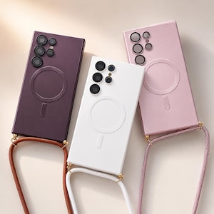 May include: Three mobile phone cases in plum, white, and pink, each with a circular design and a strap. The cases have multiple camera cutouts and a magnetic ring. The straps are in brown, white, and pink.