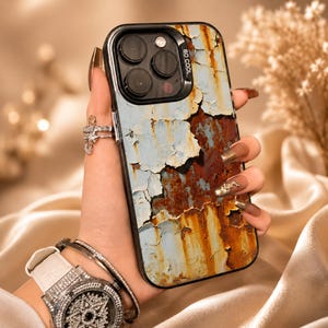 May include: A rectangular smartphone case featuring a distressed, weathered design with peeling light blue paint revealing patches of dark brown rust underneath. The camera module area is black and includes the text SO COOL printed on the side.
