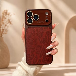 May include: A dark red smartphone case with a textured leopard print pattern on the back. The upper section features a smooth dark brown camera housing with three circular lenses, a flash, and the text CASE AITO printed in white lettering.