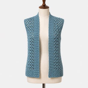 May include: A sleeveless, open-front vest in a dusty blue color, crafted with a textured crochet pattern. The garment features a solid, ribbed vertical border along the front edges and a matching ribbed hem at the bottom, showcasing an intricate, airy, diamond-shaped openwork design throughout the main body.