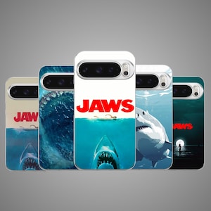 Op de afbeelding: Vijf smartphonehoesjes met diverse Jaws-filmposterontwerpen. Elk hoesje toont het iconische rode Jaws-logo, afbeeldingen van een grote witte haai en scènes van een zwemmer in de oceaan. De hoesjes hebben uitsparingen voor cameralenzen.