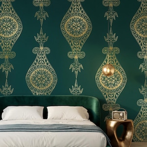 May include: A luxurious bedroom featuring a green velvet bed with white bedding and a blue throw. The emerald green wall is adorned with a gold geometric pattern. Gold spherical pendant lights and a side table complete the elegant decor.