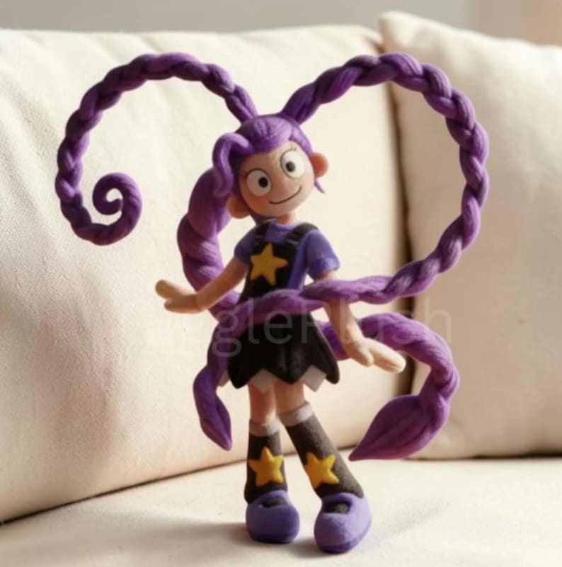Puede incluir: Figura artesanal de un personaje de dibujos animados con pelo largo trenzado de color p&uacute;rpura. El personaje viste un top azul con una estrella amarilla, una falda negra y zapatos morados. La palabra "gler" es visible en la figura.