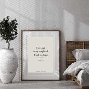 Könnte beinhalten: Ein rechteckiger gerahmter Wandkunstdruck mit beigem Hintergrund und schwarzem Text: The Lord is my shepherd I lack nothing, Psalm 23:1, und unten LIBERIUM - The Ways of Grace. Der Rahmen besteht aus einfachem, dünnem braunem Holz.