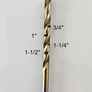 Puede incluir: Una taza de cerámica blanca con asa negra y el texto "But First, Coffee" en negrita negra. La taza se encuentra sobre un fondo borroso, sugiriendo un ambiente acogedor.