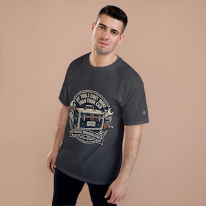 Könnte beinhalten: Dunkelgraues T-Shirt mit einer Grafik einer Werkzeugkiste, Werkzeugen und dem Text "MY TOOLS COST MORE THAN YOUR CAR" und "PROUDLY OVERQUALIFIED". Das Shirt hat ein Champion-Logo auf dem Ärmel.