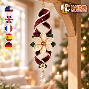 May include: A hanging crochet ornament featuring a twisted deep red ribbon, a central cream-colored poinsettia flower with green leaves, small red berries, and a clear teardrop crystal pendant at the bottom. The text Haider Creative Hub is visible.