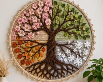 Op de afbeelding: Een ronde gehaakte wandhanger met een centrale boom verdeeld in vier seizoenskwadranten. Linksboven zijn roze bloesems te zien, rechtsboven groene bladeren, linksonder oranje herfstbladeren en rechtsonder witte sneeuwvlokken.