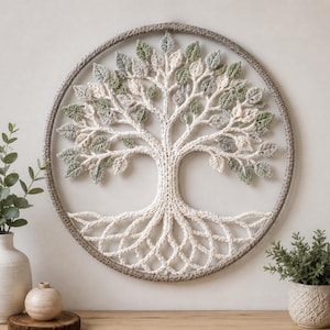 May include: A handcrafted, circular wall hanging featuring a crocheted tree of life design. The tree has a cream-colored trunk and roots, with green and gray leaves. The tree is framed by a gray circular border, creating a nature-inspired decor piece.
